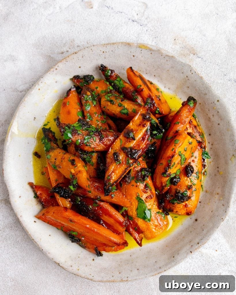 Hot honey roasted carrots sit in bowl and have been garnished with fresh parsley. 