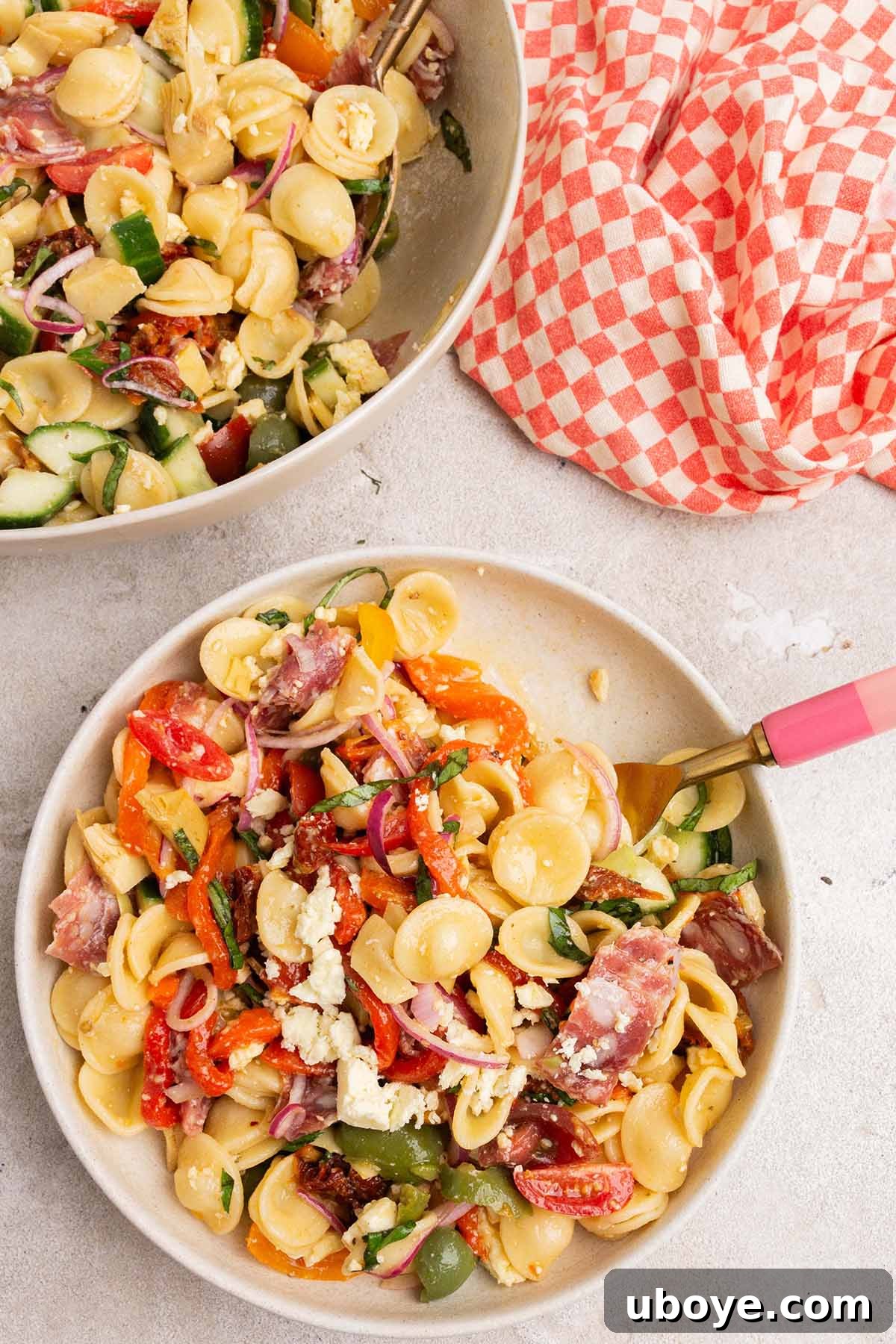 Vibrant Rainbow Antipasto Pasta Salad served in a large bowl with a checkered napkin, showcasing colorful ingredients.