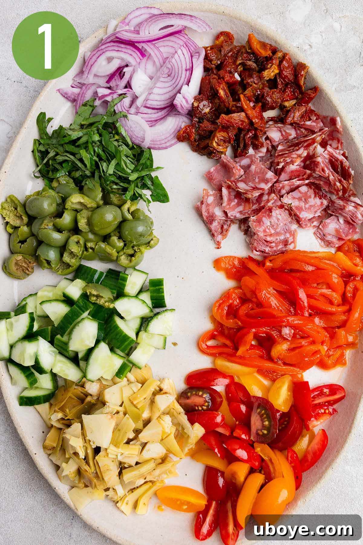Preparing and chopping the various meats and fresh vegetables for the pasta salad, arranged on a cutting board.
