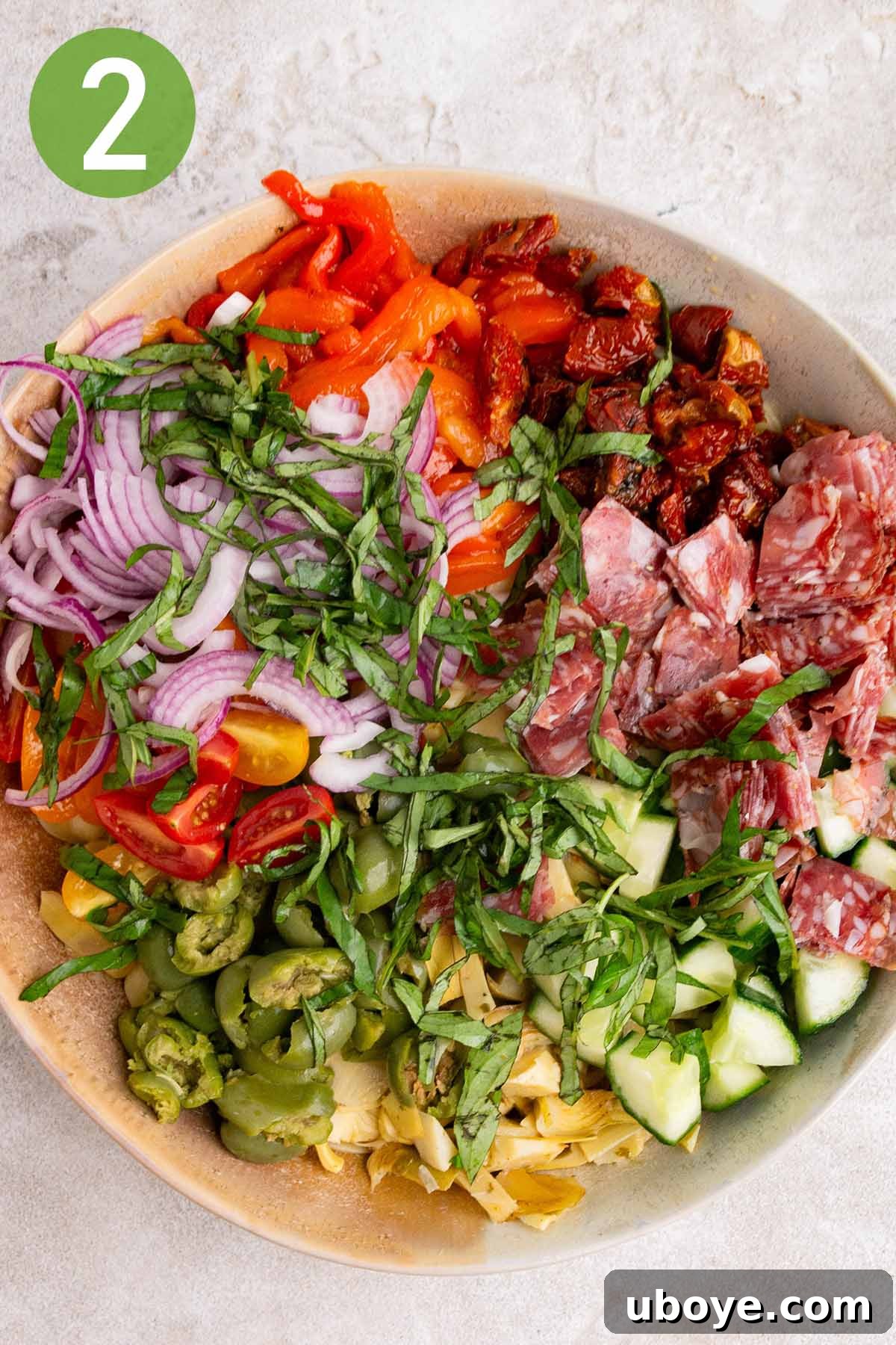 Combining all the chopped ingredients for the pasta salad into a large mixing bowl.