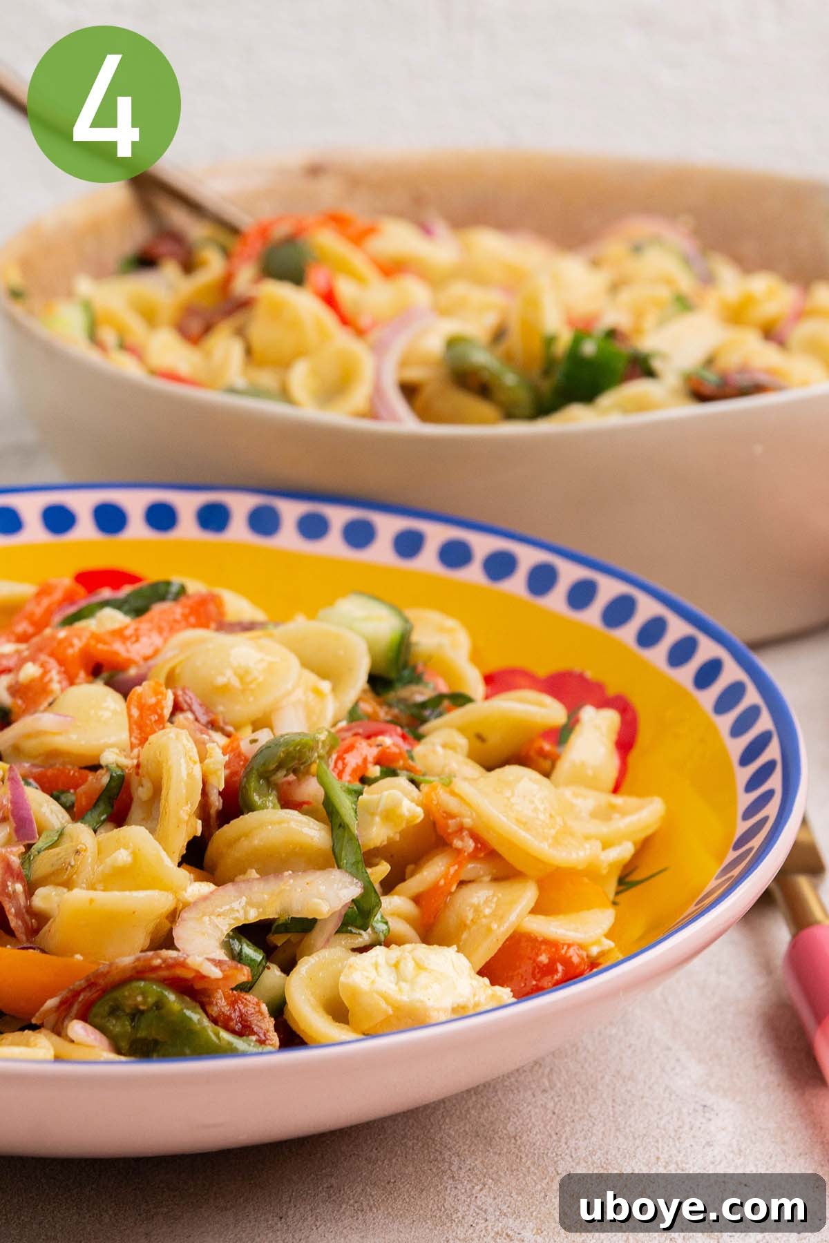 A large bowl of colorful Rainbow Antipasto Pasta Salad, garnished with crumbled feta.