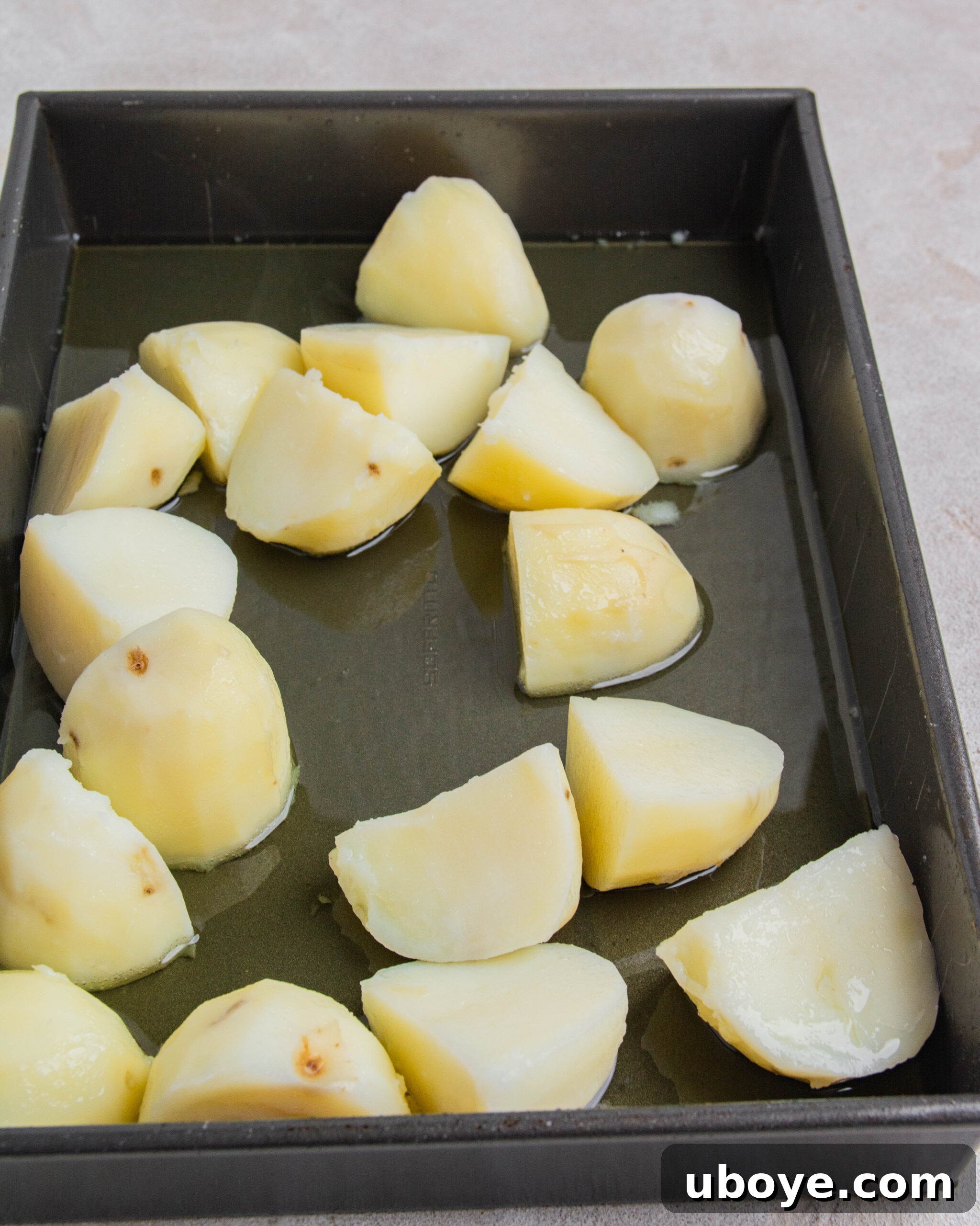 Parboiled and steam-dried potatoes carefully added to a hot roasting tray filled with sizzling duck fat and olive oil.