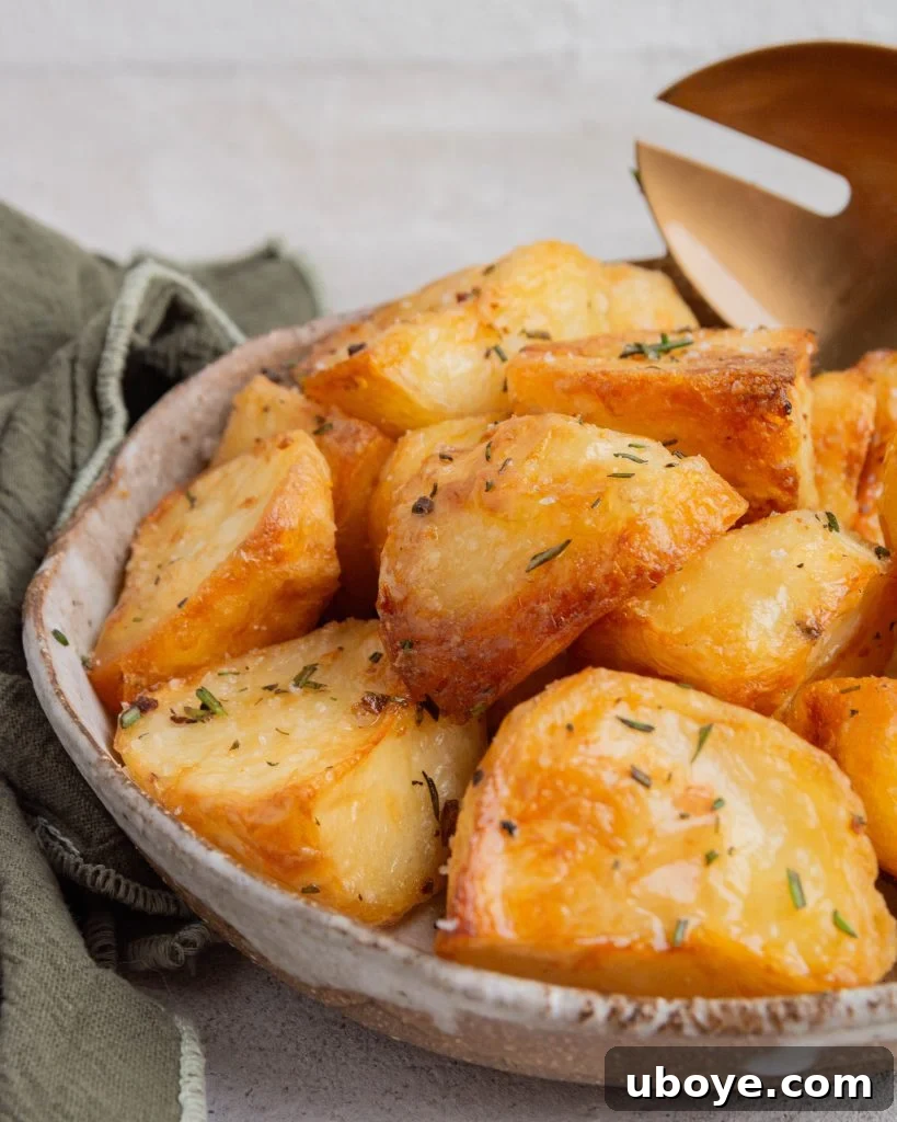 A brown serving bowl brimming with crispy duck fat roasted potatoes, generously sprinkled with fresh rosemary, creating an appetizing and inviting presentation.