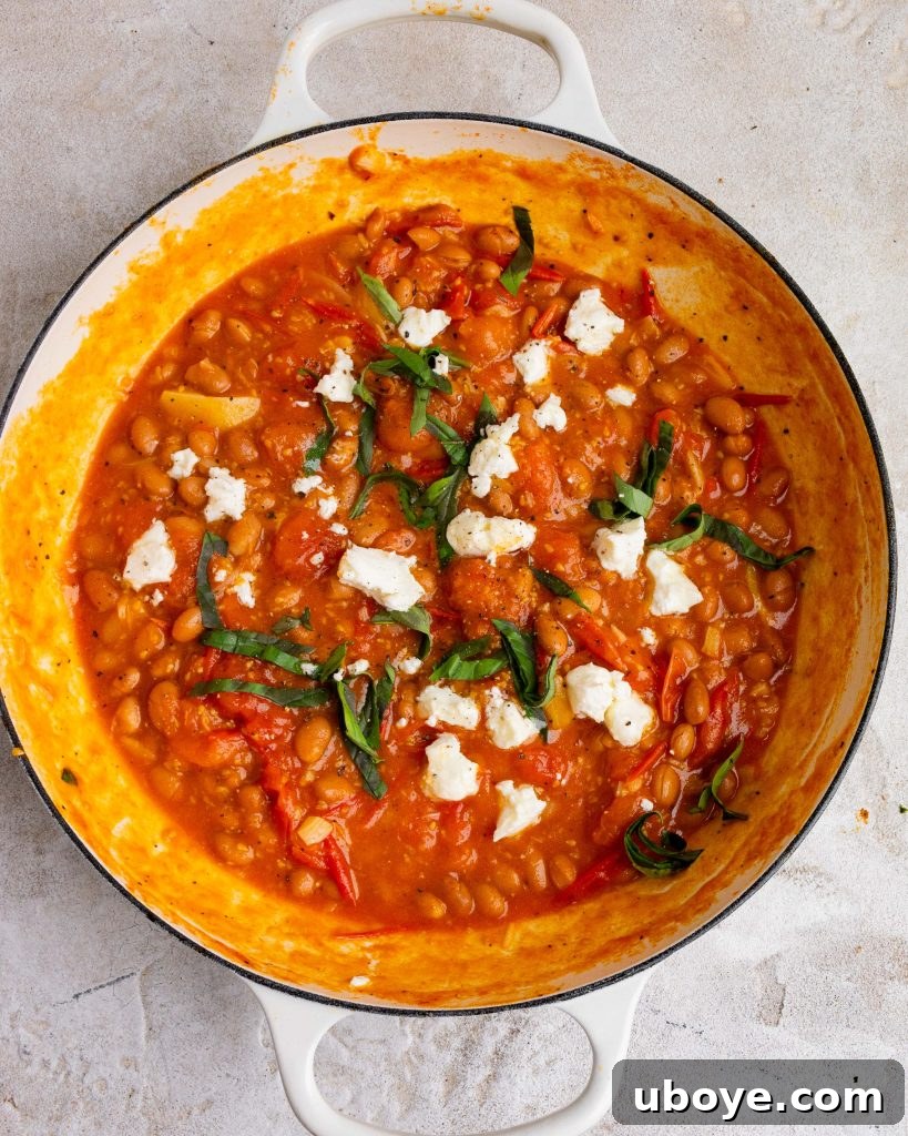 Rustic Tomato Garlic Beans 4 A bowl of tomatoey garlic beans with fresh herbs and a side of sourdough bread.