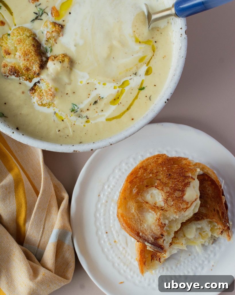 Creamy Cauliflower Delight 11 A bowl of cauliflower soup next to a plate with a grilled cheese sandwich, ready to eat.
