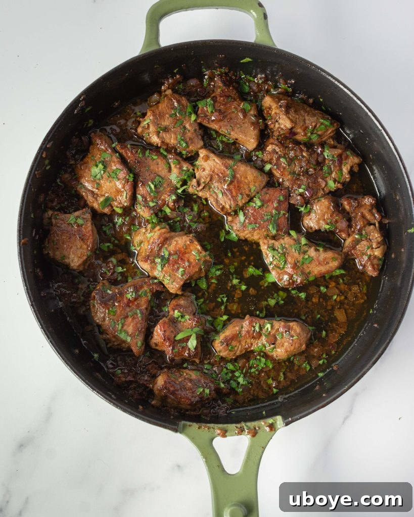 A cast iron skillet with sizzling garlic butter, ready for steak bites.