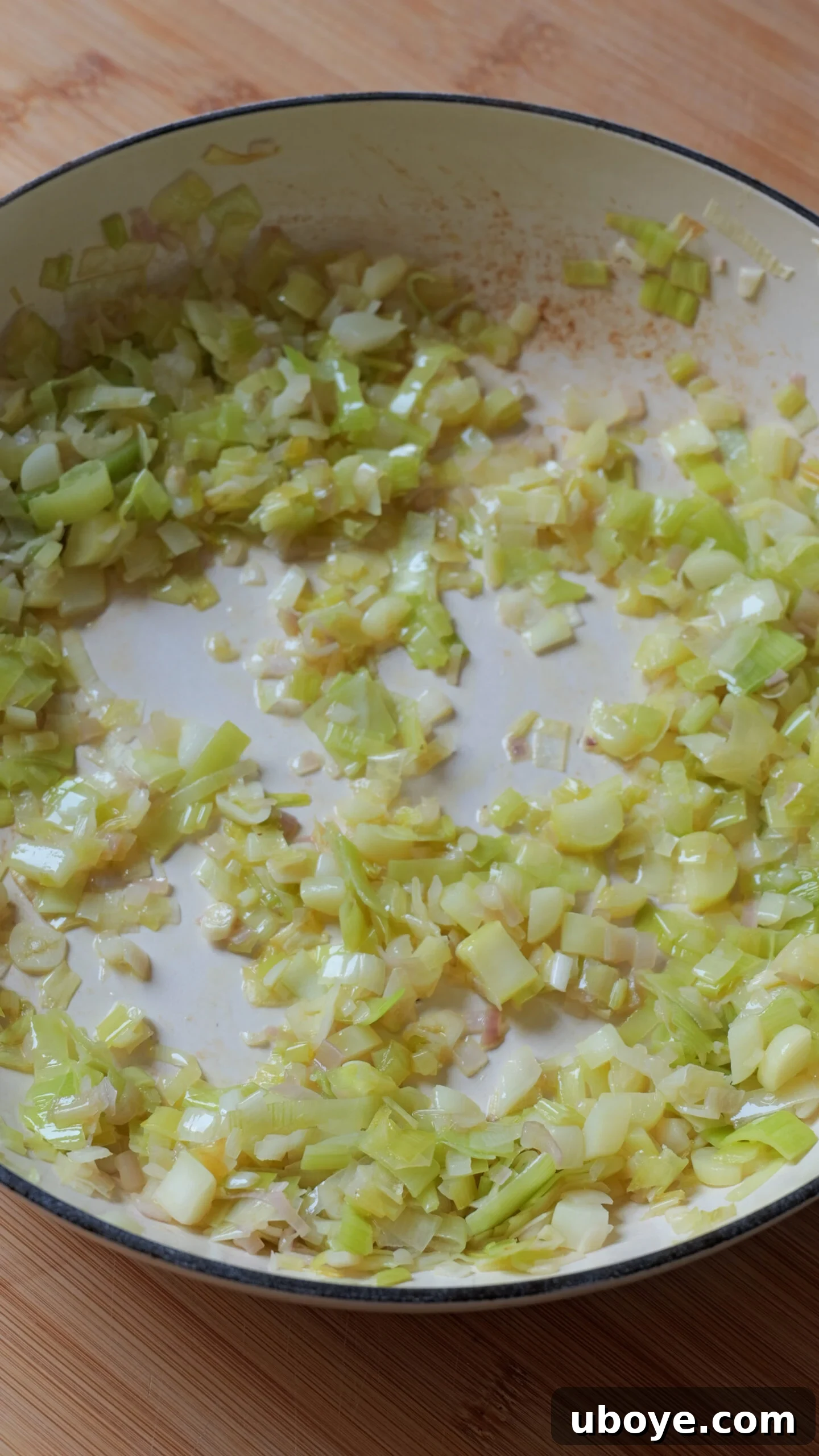 Creamy Leek Risotto 3 Sliced leeks, shallots, and minced garlic are gently frying in a white pan, releasing their fragrant aromas.