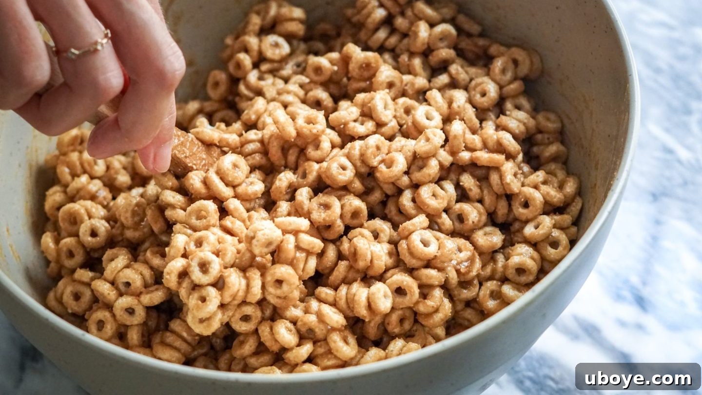 Bee-Free Honey Nut Cereal Bars 7 A large bowl filled with O-shaped cereal being mixed with the peanut butter and maple syrup binder.
