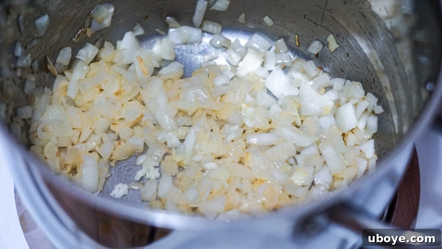 Creamy Mushroom Dream Pasta 3 Diced onions gently sizzling in olive oil in a large pot, beginning to soften and turn translucent, forming the aromatic base for the creamy sauce.