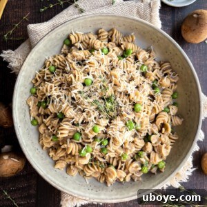 A bowl of creamy mushroom pasta with peas, ready to be served.