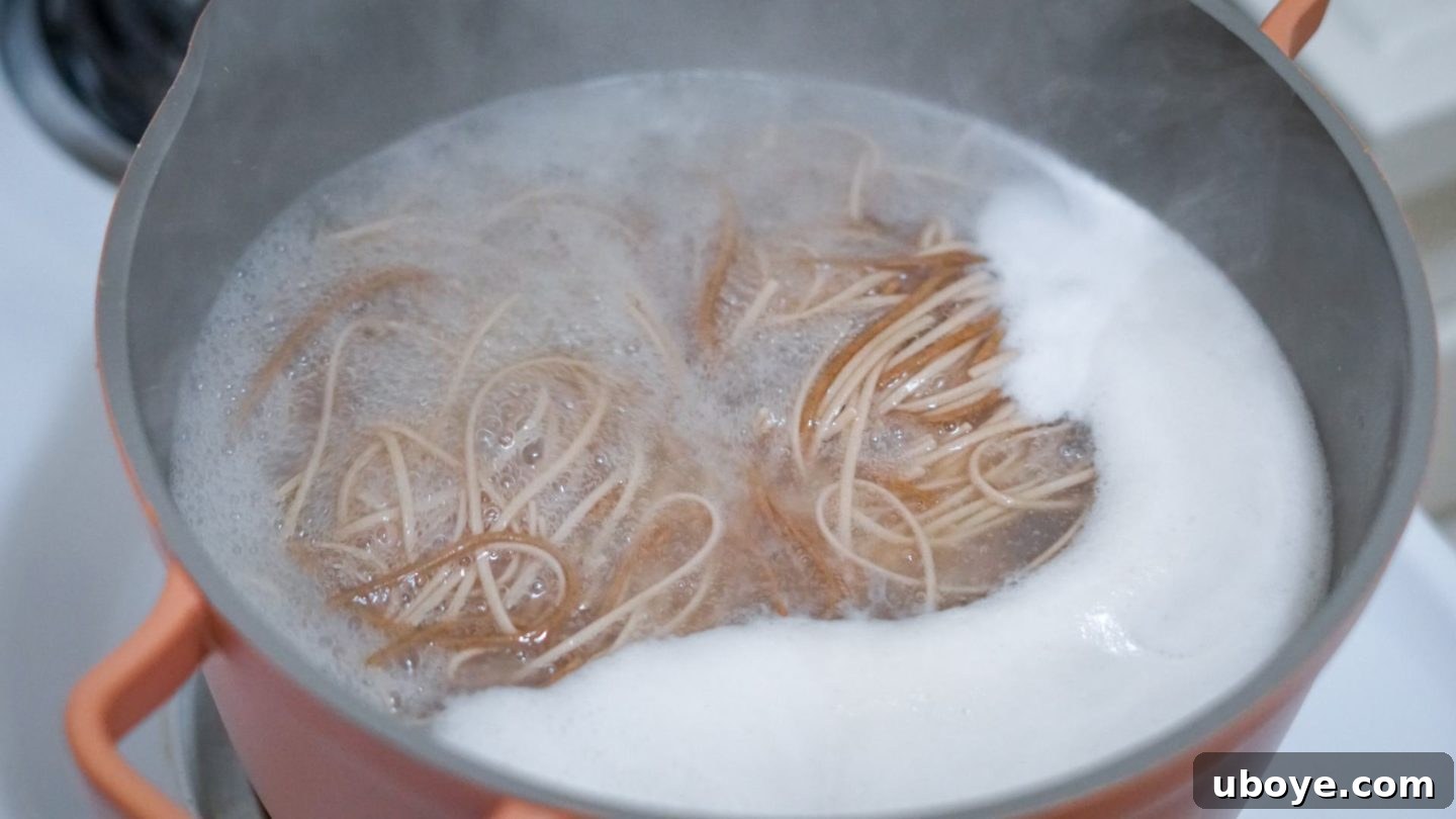 Close-up of the rich and creamy Thai peanut sauce being vigorously whisked in a glass bowl, showcasing its smooth texture and vibrant color.