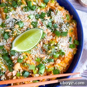 Peanut noodles with scallions and lime on a blue plate, served fresh and vibrant.