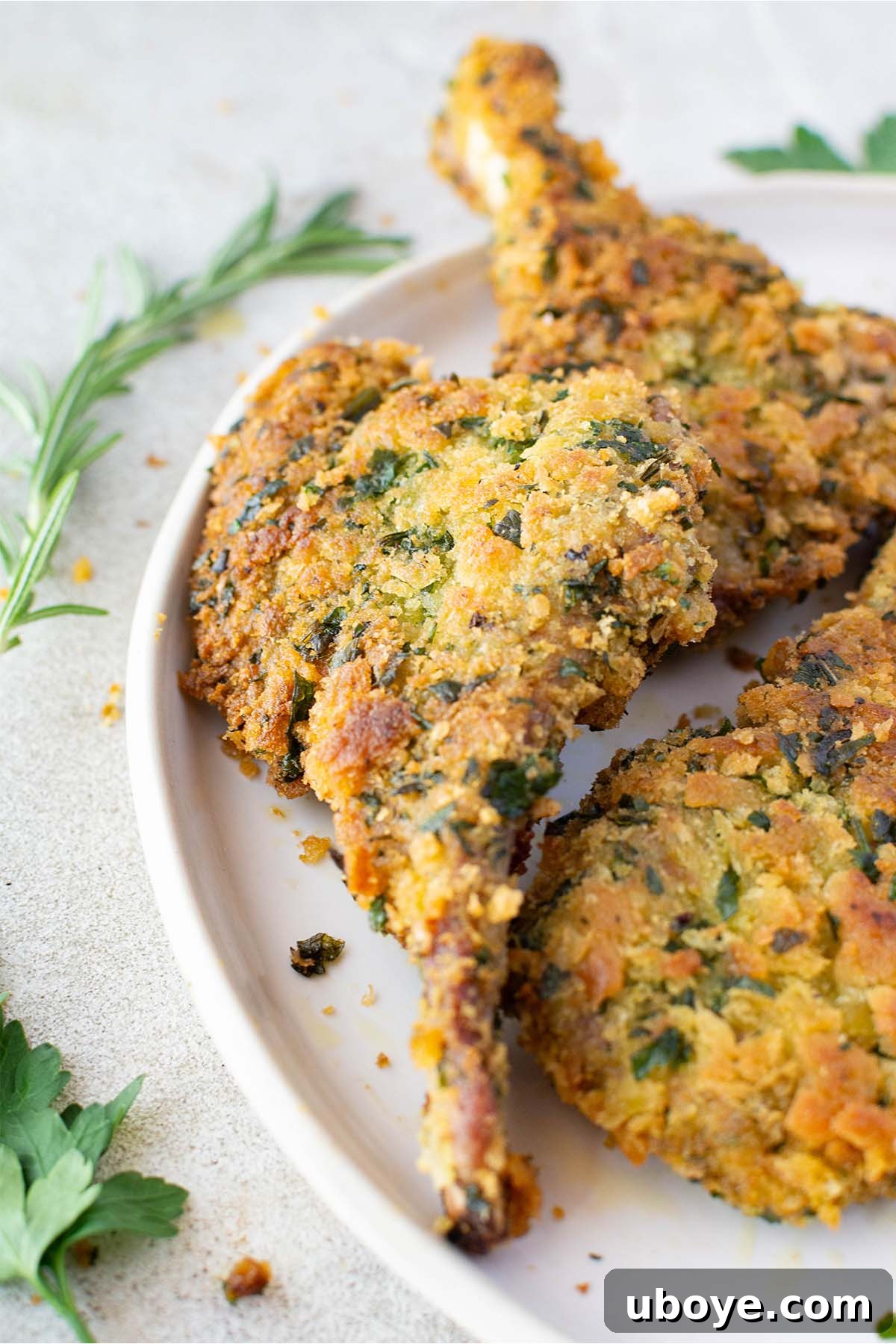 A plate of golden, crispy crumbed lamb cutlets garnished with fresh herbs, ready to be served.