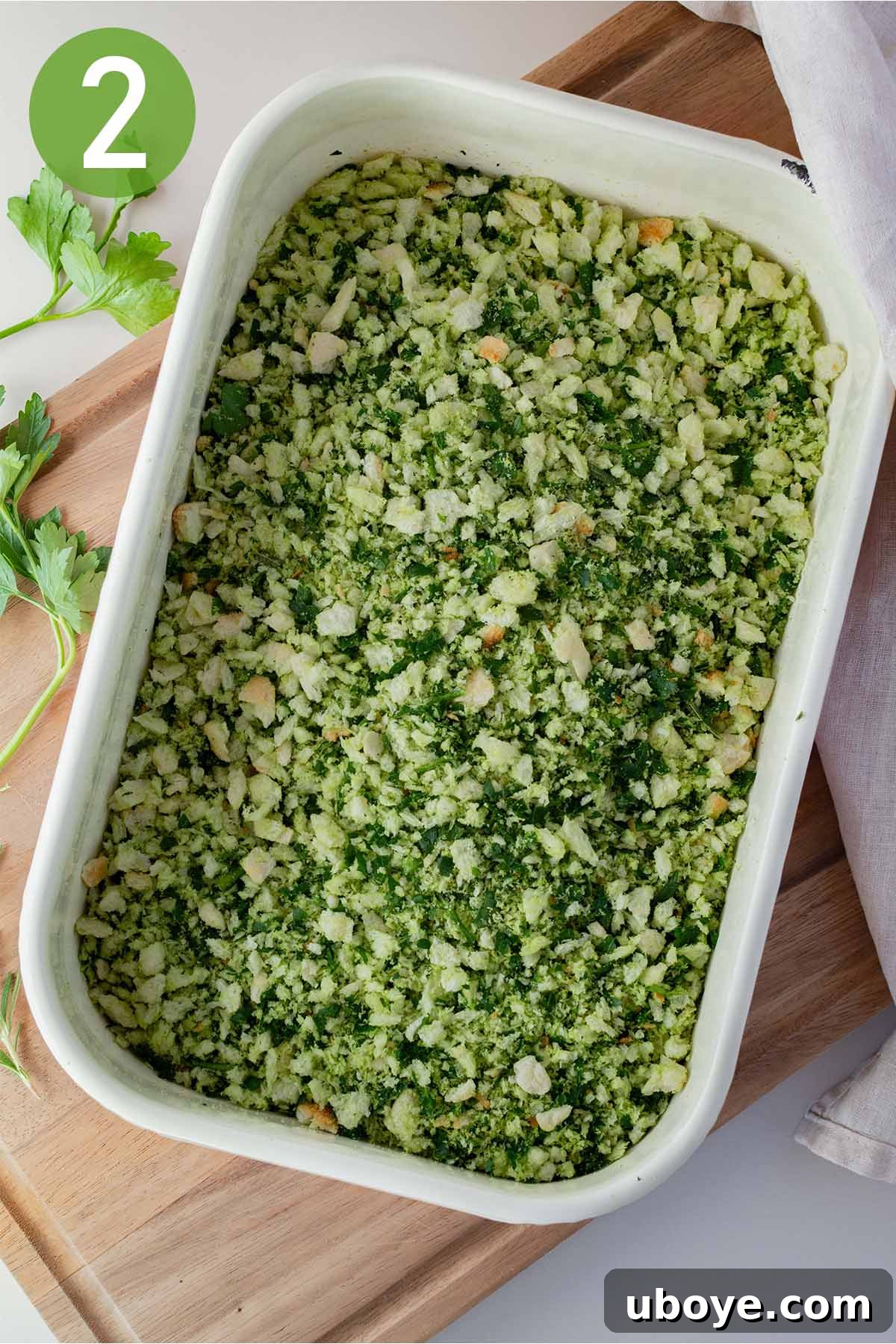 Freshly made herbed breadcrumbs mixed with green parsley and rosemary in a shallow dish, ready for coating.