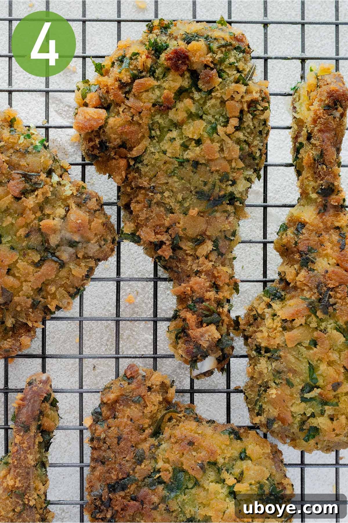 Golden brown, crispy breaded lamb cutlets resting on a wire rack to drain excess oil after frying.