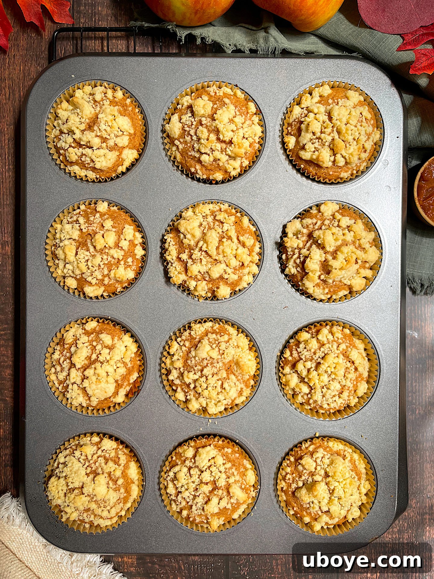 Close-up of a perfectly baked vegan apple muffin with a golden streusel topping, highlighting its moist, fluffy texture.