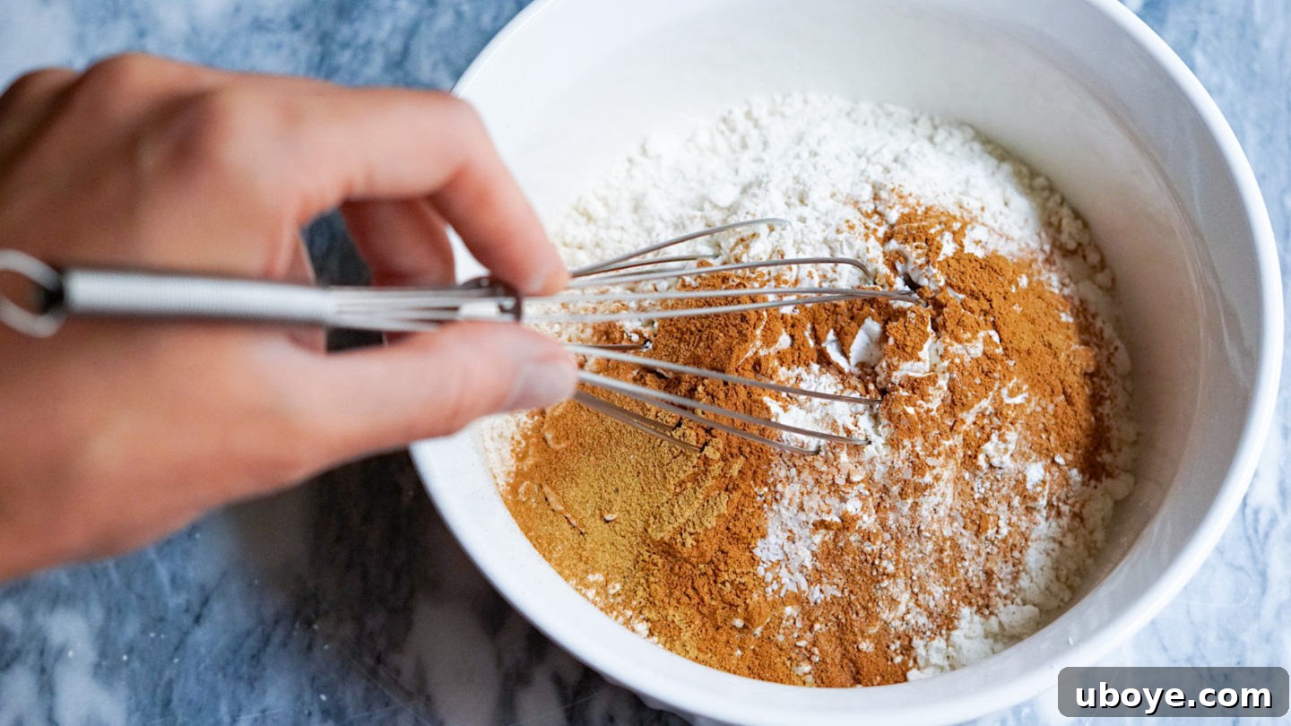 The mixing process for vegan apple muffins, showing the wet ingredients being thoroughly combined in a large bowl.