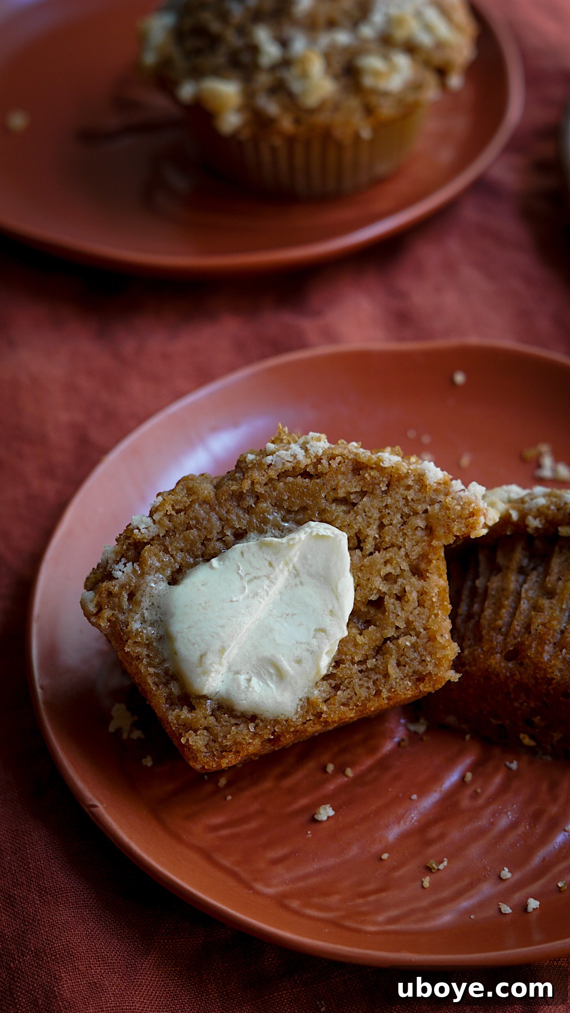A close-up shot of a single fluffy vegan apple muffin, showing its moist, tender interior and generous streusel topping.