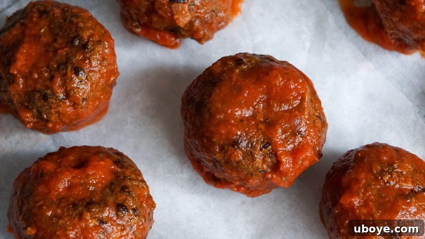 Game-Changing Lentil Meatball Heroes 3 Close-up of lentil meatballs coated in marinara sauce.