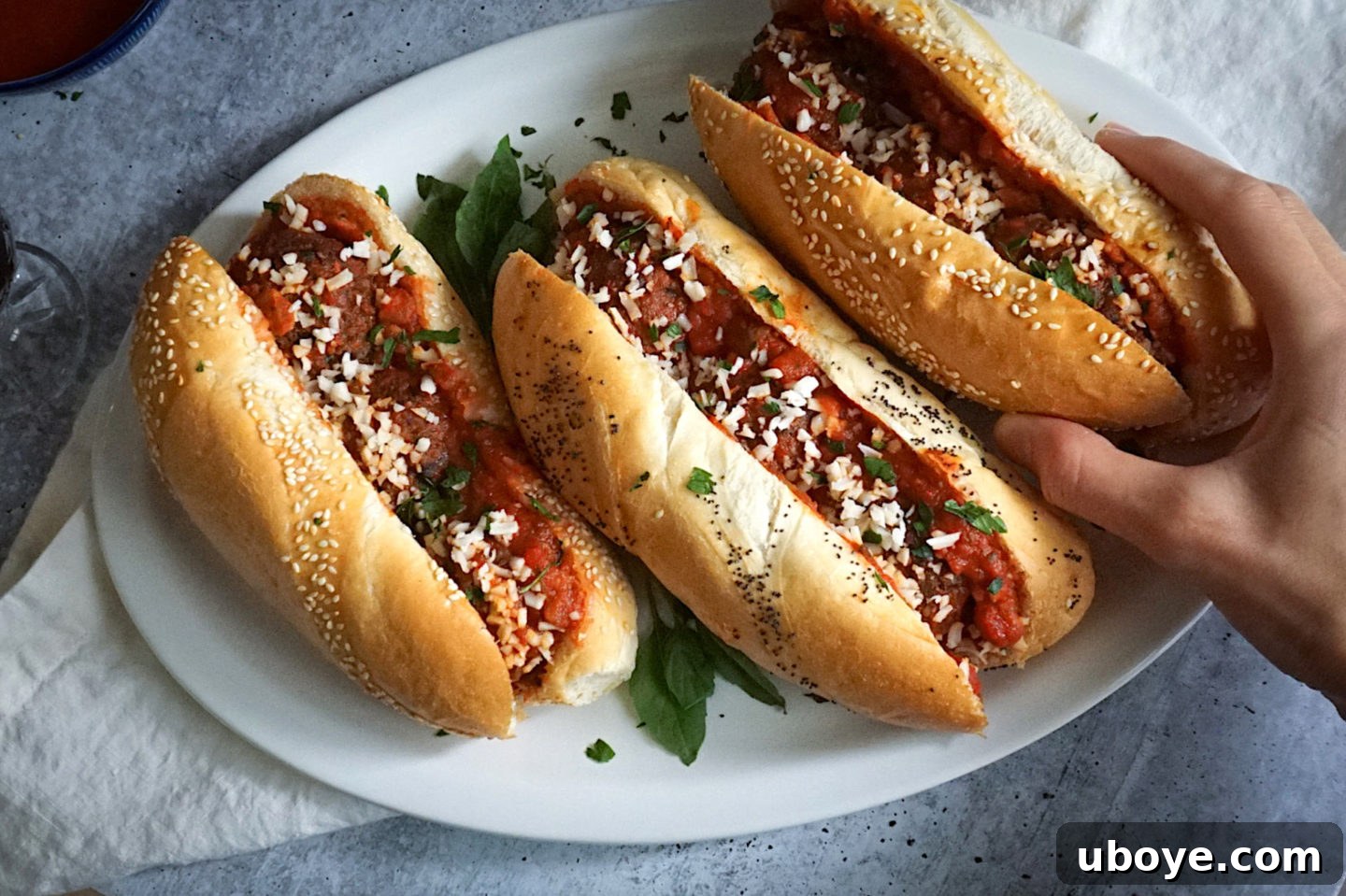 Game-Changing Lentil Meatball Heroes 6 Two finished meatball subs on a white plate, ready to be eaten.