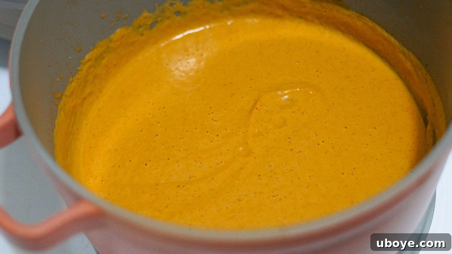 Smooth Vegan Pumpkin Harvest Soup 5 The blended creamy vegan pumpkin soup simmering in a pot, ready for serving.