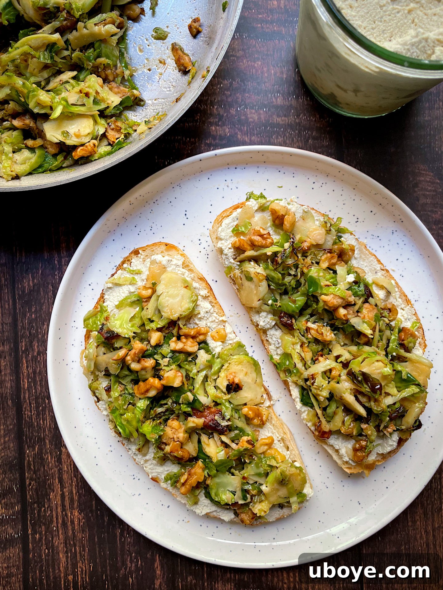 A plate of savory vegan brussel sprout and ricotta toast, garnished with fresh herbs.