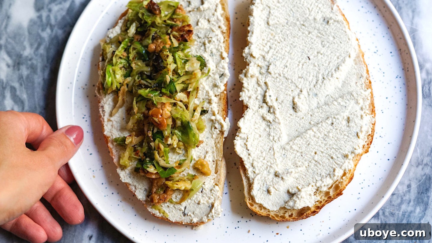 Two slices of sourdough toast with vegan ricotta, topped with the warm brussel sprout and tempeh mixture, ready to be served.