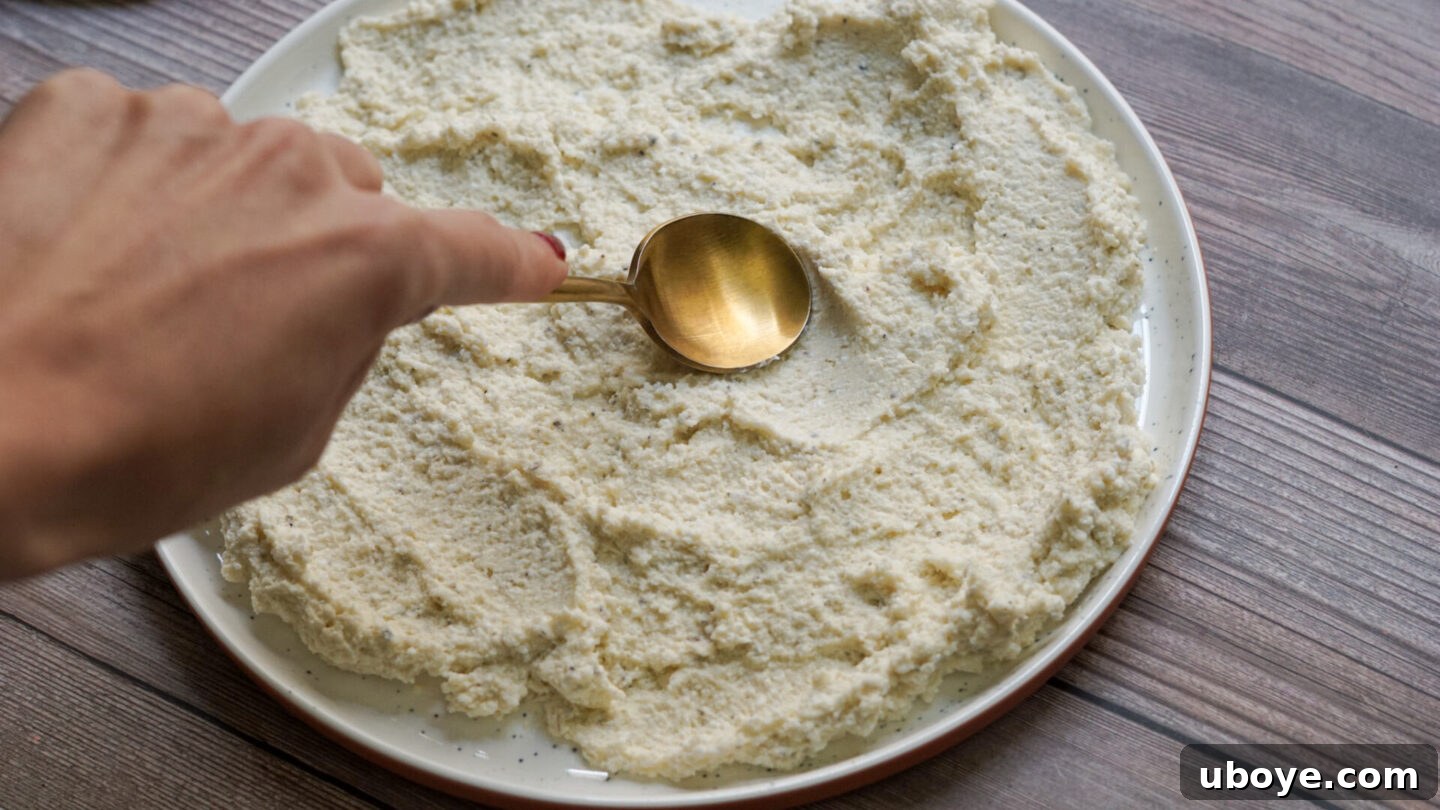 Whipped vegan feta artistically spread on a serving plate with a spoon, ready for the roasted carrots.