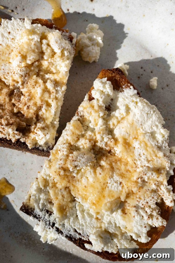Homemade ricotta cheese elegantly spread on toasted bread, garnished with black pepper and a delicate drizzle of honey.