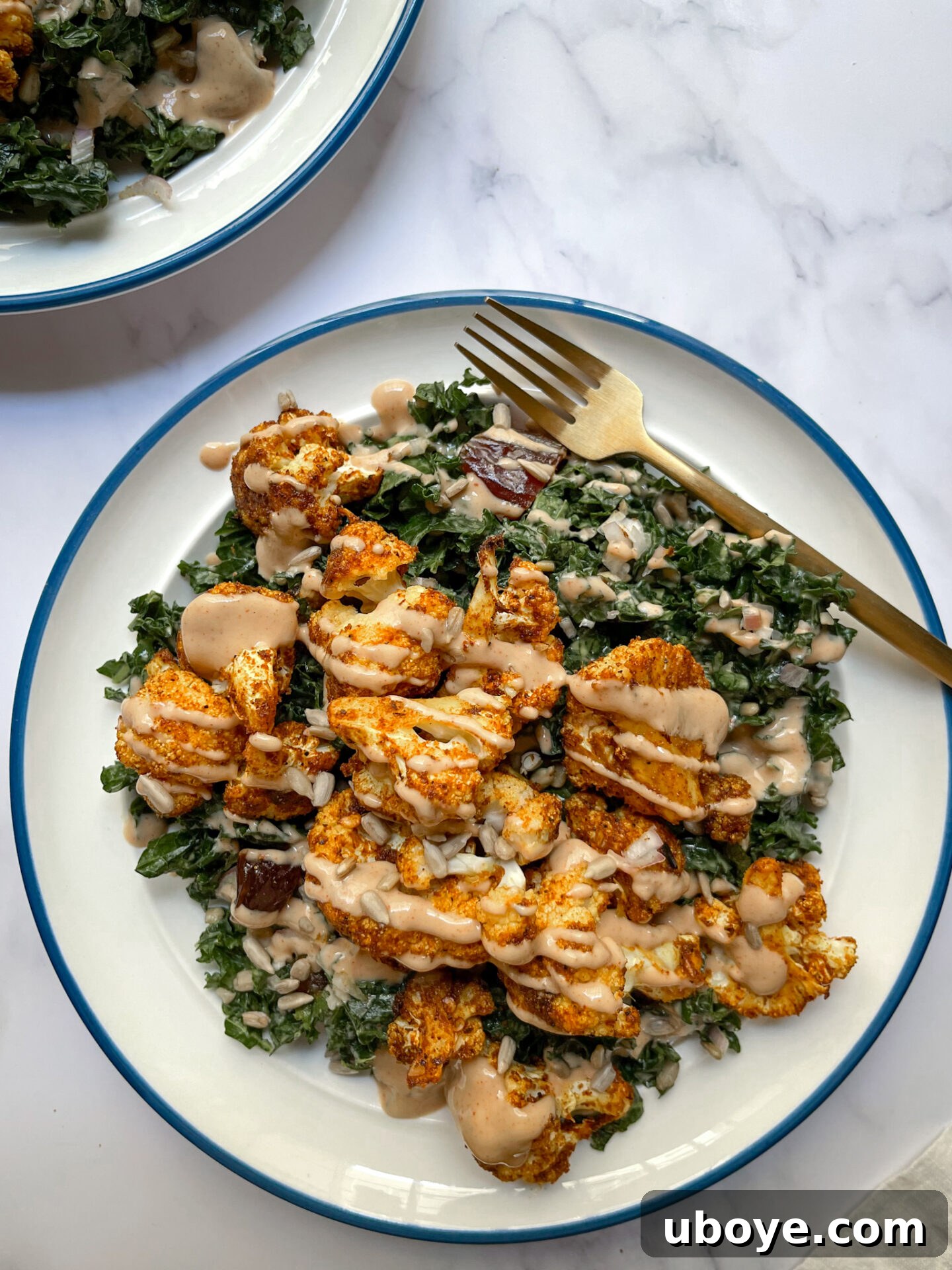 Overhead shot of two plates of Shawarma Spiced Cauliflower and Kale Salad