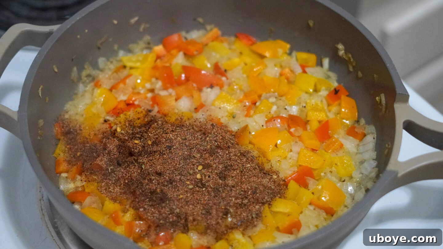 Cashew cream sauce being poured into a pan with sautéed vegetables, ready to be mixed into the Cajun pasta.