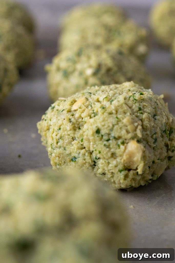 Fresh falafel balls being carefully placed into hot oil for frying.