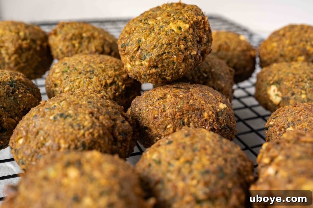 A close-up of a perfectly fried falafel, showing its crispy exterior and vibrant green interior.