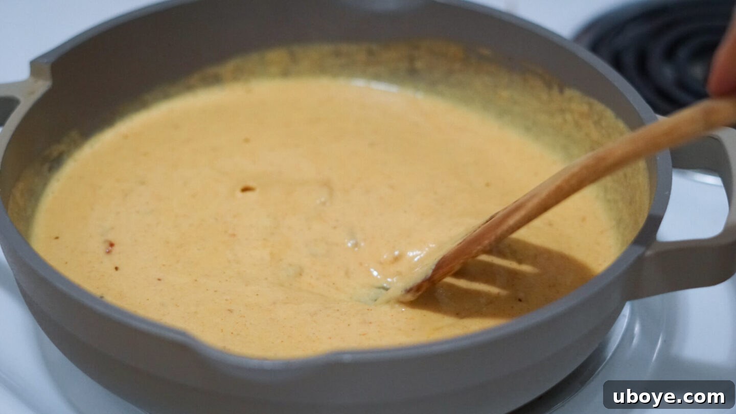 Velvety Plant-Based Queso 7 Blender jar filled with the vibrant orange mixture of cashews, butternut squash, and spices, ready to be blended into queso.