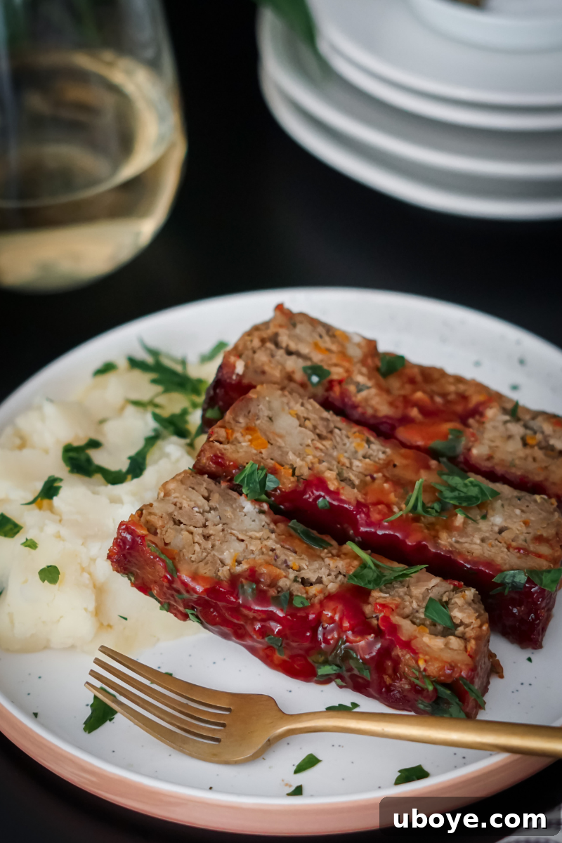 Slices of glazed vegan meatloaf served with green beans and mashed potatoes on a white plate, ready to eat.