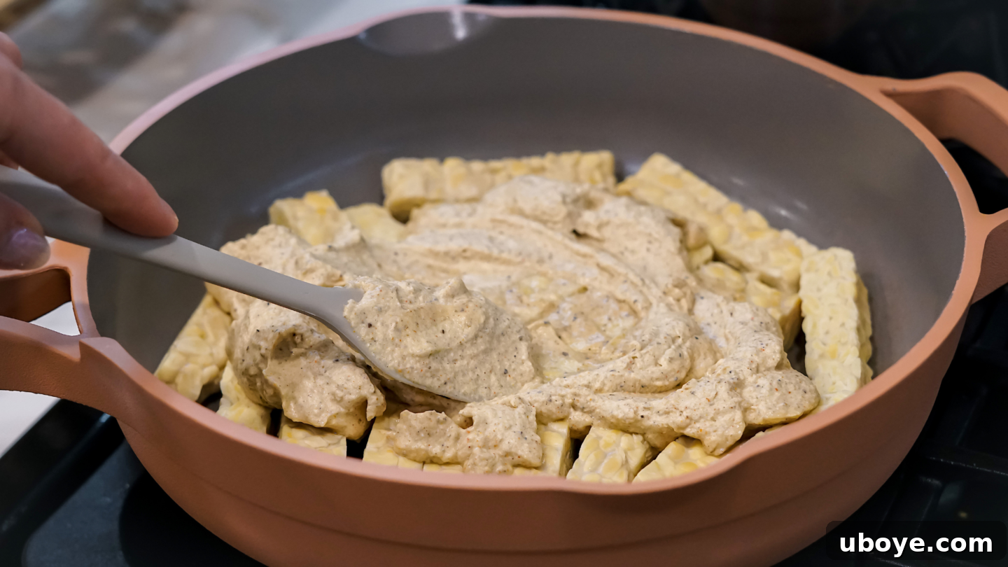 A vibrant, Indian-spiced vegan yogurt marinade being mixed in a bowl, showcasing its rich texture and color, ready for the tempeh.