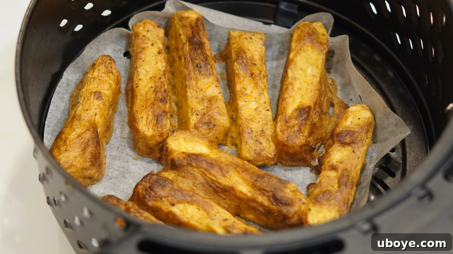 Golden brown and crispy Tandoori tempeh pieces cooking evenly within an air fryer basket, showcasing perfect caramelization.
