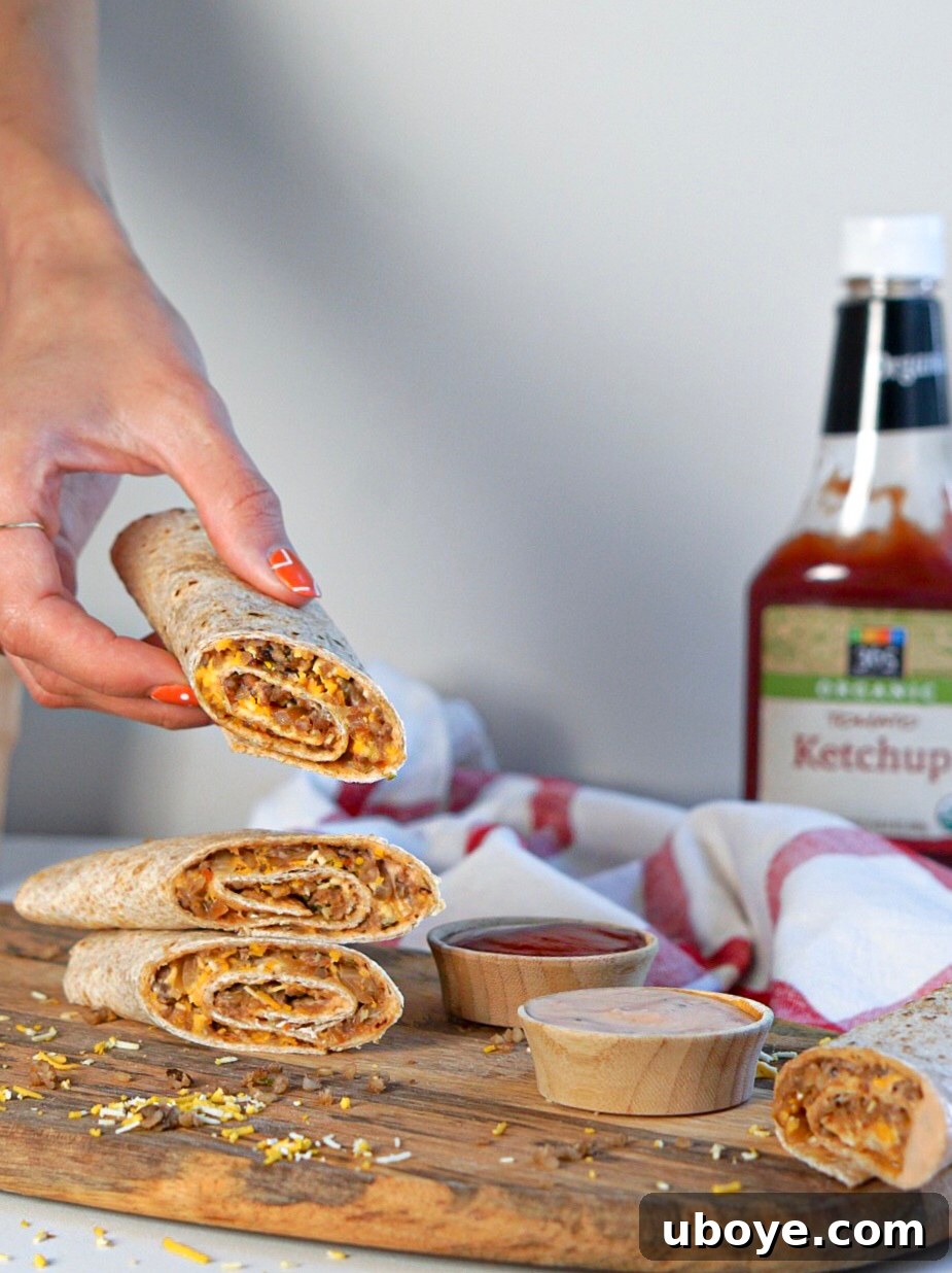 Close-up of a vegan patty melt roll-up, showing caramelized onions, melted cheese, and a veggie burger filling
