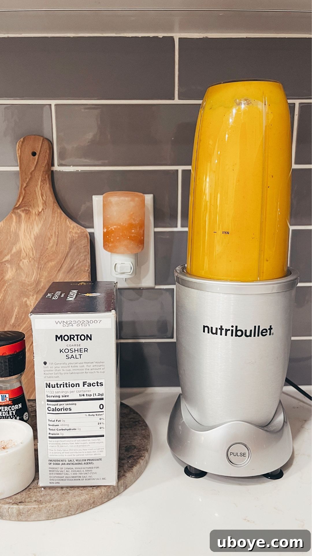 Roasted butternut squash, onions, and apples being scooped into a Nutribullet blender for creamy soup preparation.