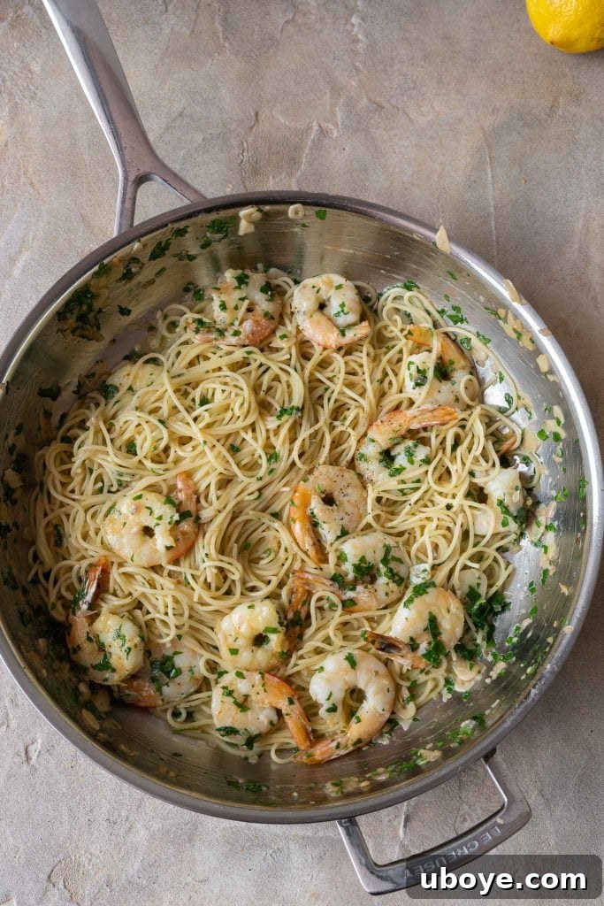 A bottle of white wine next to fresh prawns, garlic, and herbs