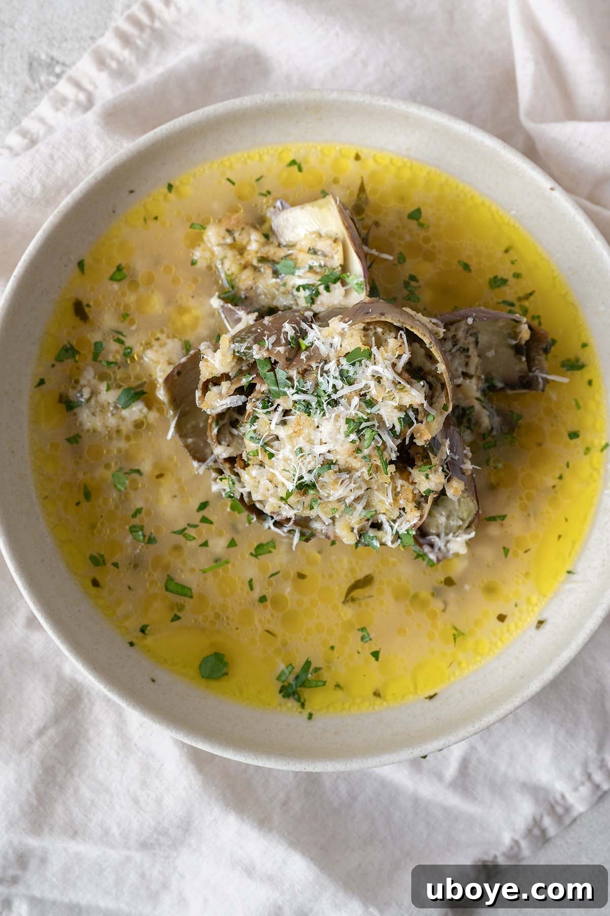 Baked Parmesan & Herb Stuffed Artichokes 2 Simmered stuffed artichoke on a plate, garnished with fresh herbs.