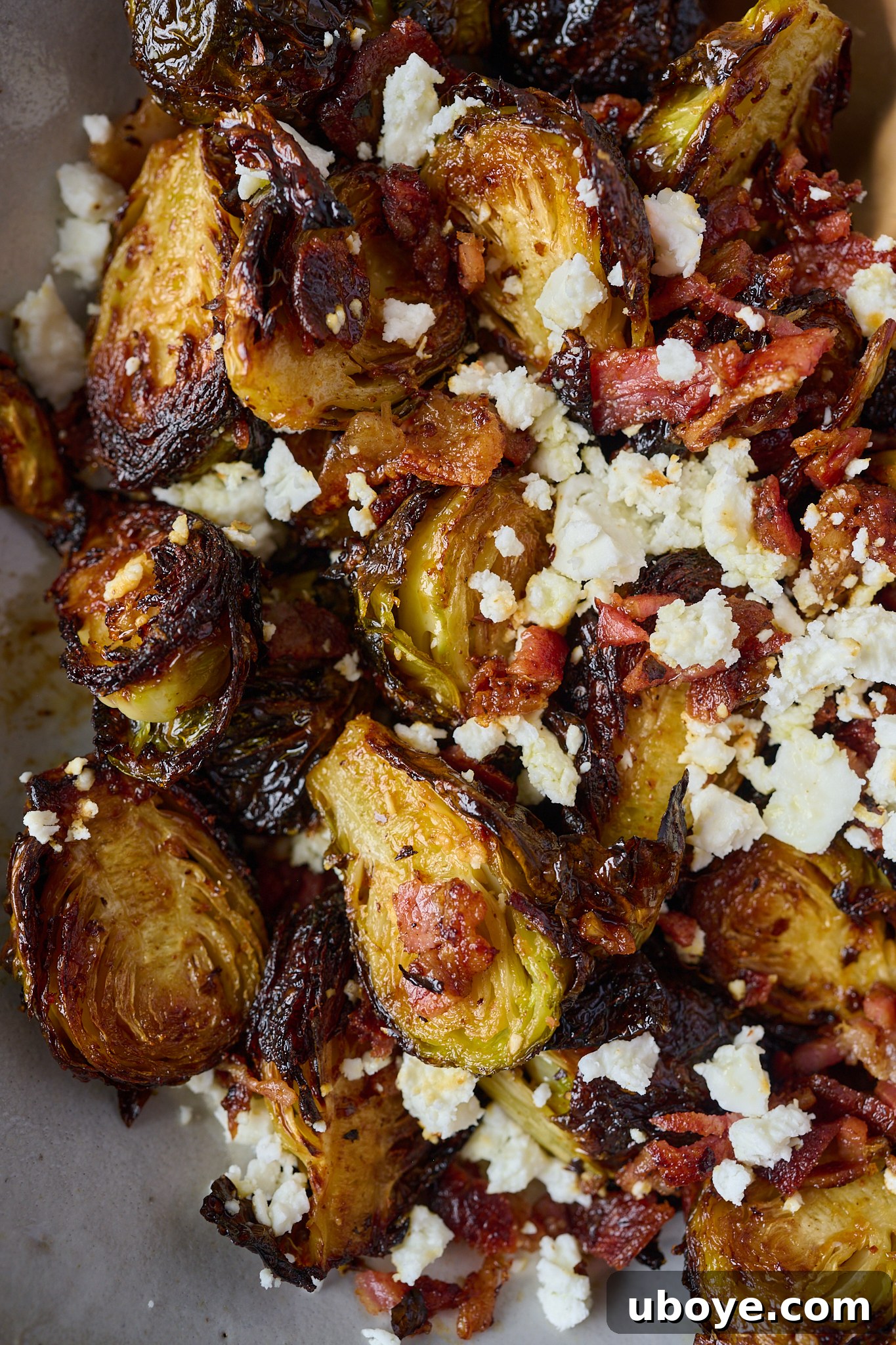 Crispy Brussels sprouts with bacon and crumbled feta in a large white bowl.