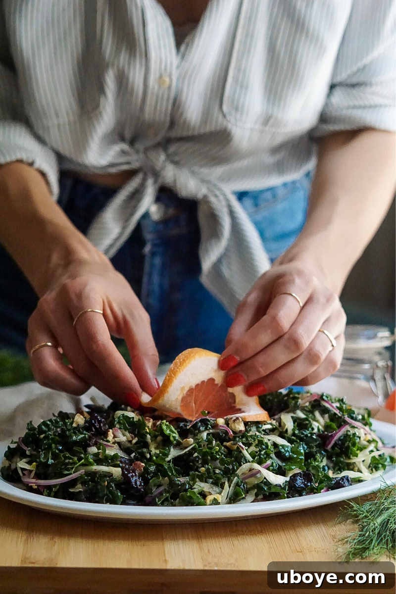 A vibrant and fully dressed kale salad, topped with various delicious ingredients