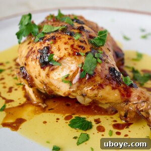 Finished maple butter roast chicken, golden and glistening, garnished with fresh herbs.
