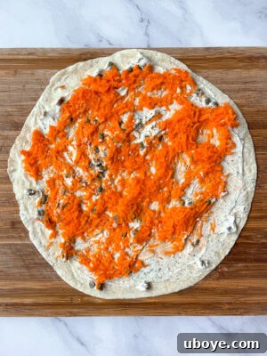 Effortless Pinwheel Creations 10 Layering ingredients on a tortilla: cream cheese, carrots, spinach, and red onion