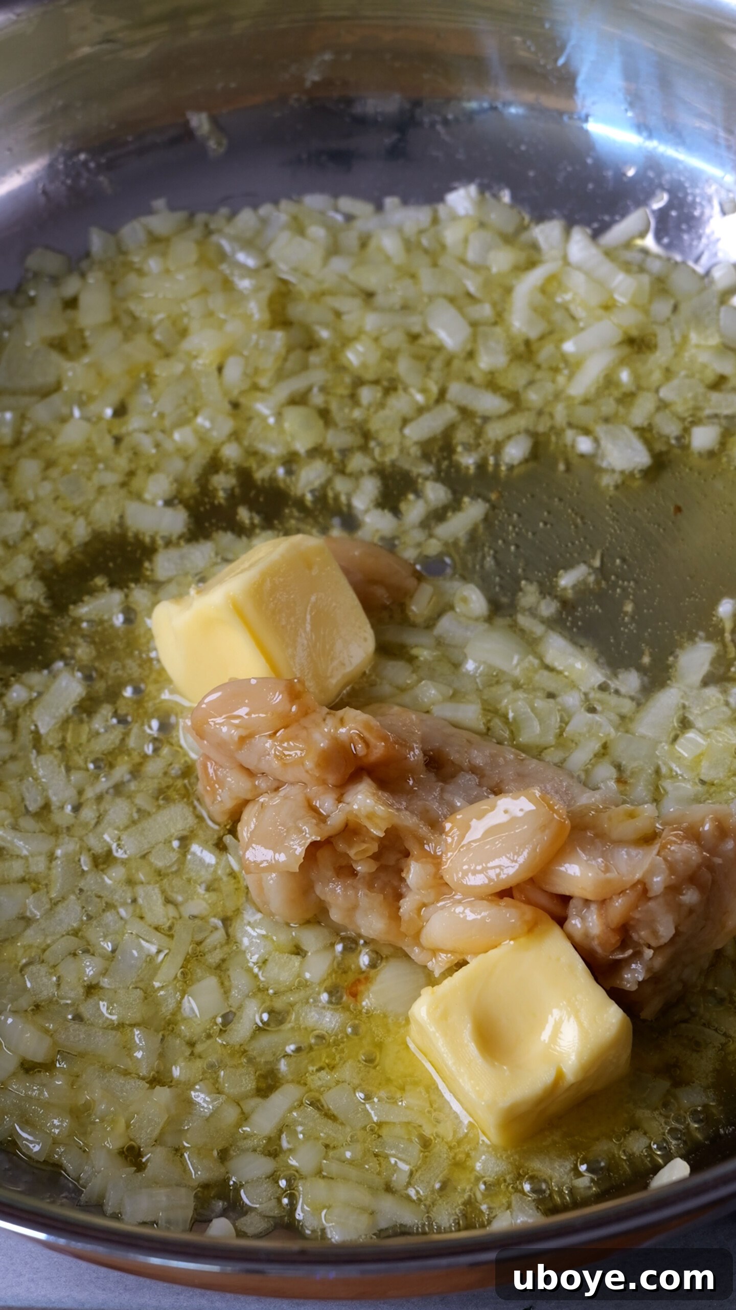 Velvety Garlic Skillet Orzo 4 Step 1 of making creamy garlic orzo: Sautéing diced onions until translucent in a large frying pan with olive oil, followed by adding garlic confit cloves and butter to melt and foam, filling the kitchen with rich aromas.