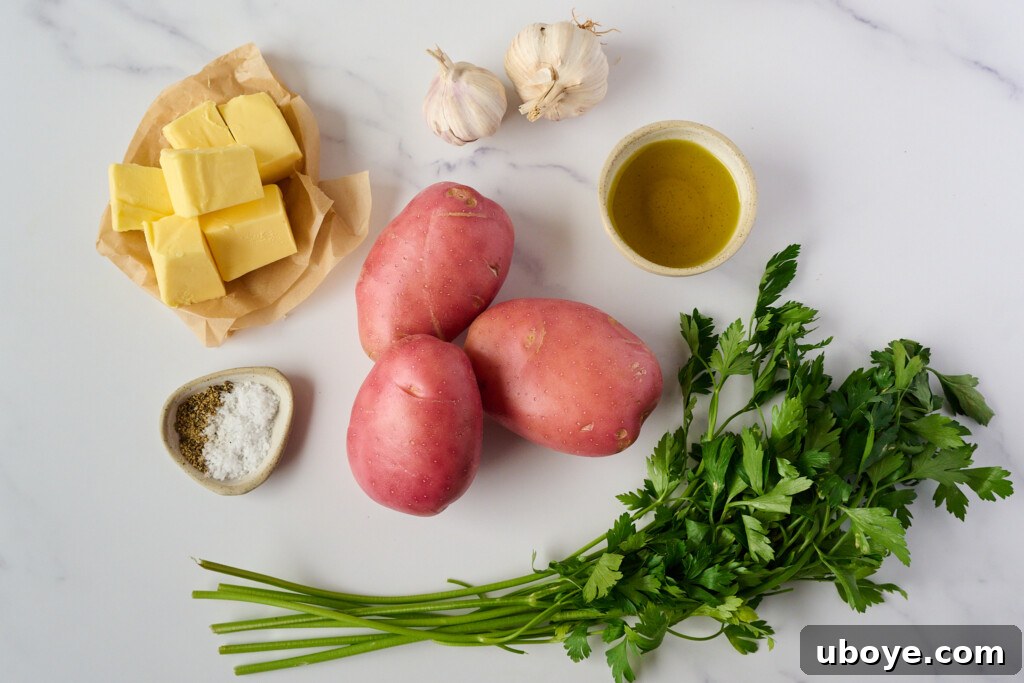 Close-up of fresh ingredients for hasselback potatoes, including whole potatoes, garlic, butter, and herbs