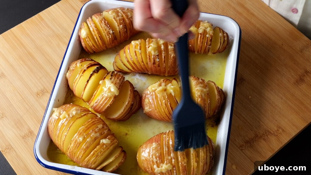 Close-up of hasselback potatoes being basted in the oven