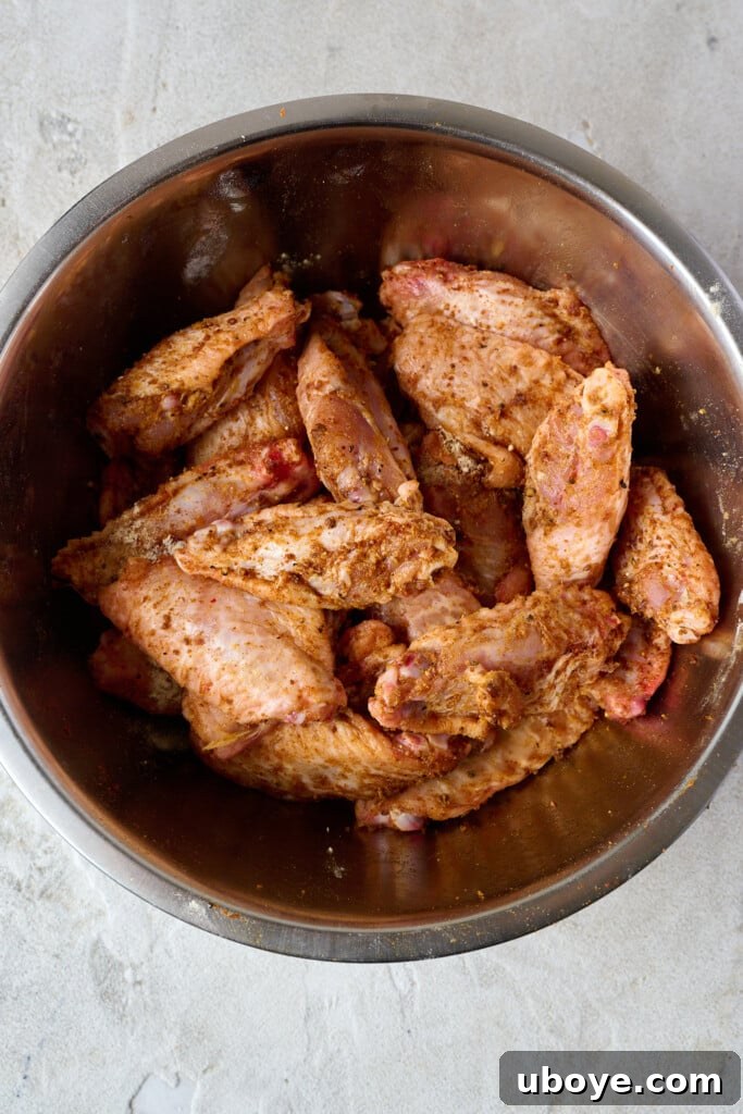 Raw uncooked wings in bowl that have been coated in spices and baking powder