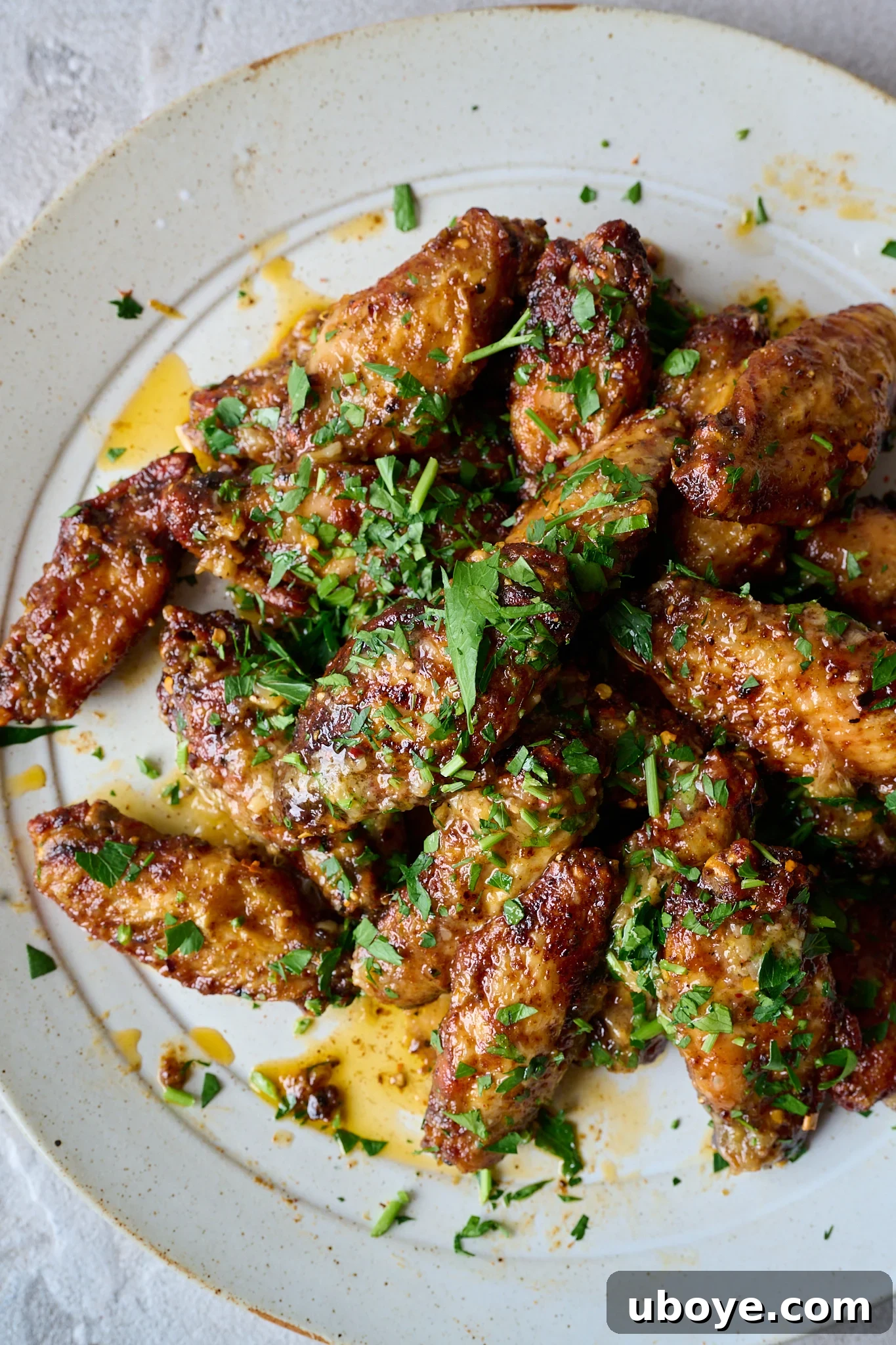 Plate full of chicken wings and topped with fresh parsley.
